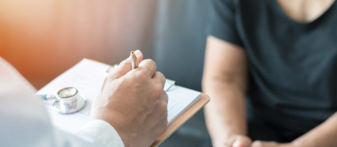 Geriatric doctor (geriatrician) consulting and diagnostic examining elderly senior adult patient (older person) on aging and mental health care in medical clinic office or hospital examination room